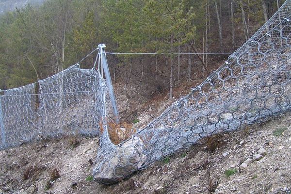 Steinschlagnetz nach einem Treffer. Räumung und Instandhaltung sind dringend notwendig, um die Schutzwirkung wieder herzustellen.