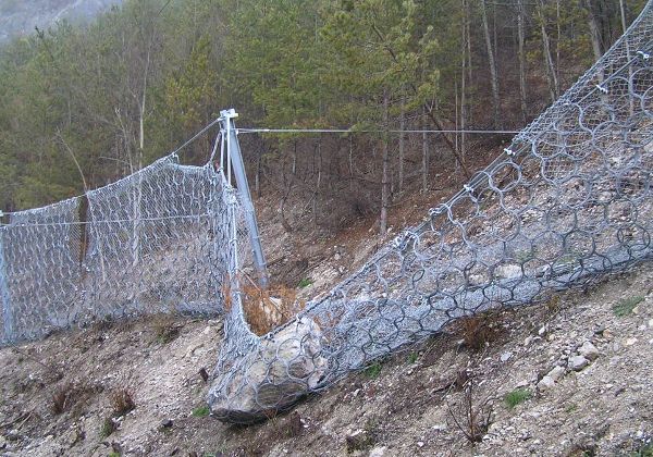 Steinschlagnetz nach einem Treffer, die Räumung und Instandhaltung sind dringend notwendig, um die Schutzwirkung wieder herzustellen.