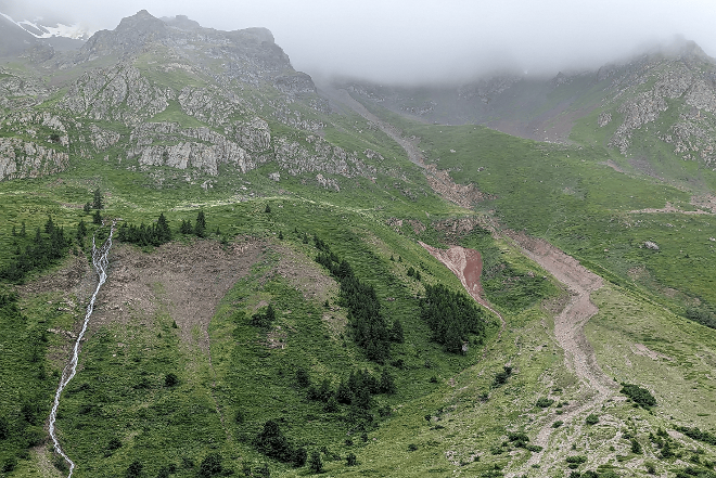 Murgang und Feilanbruch vor wolkenverhangenen Bergen